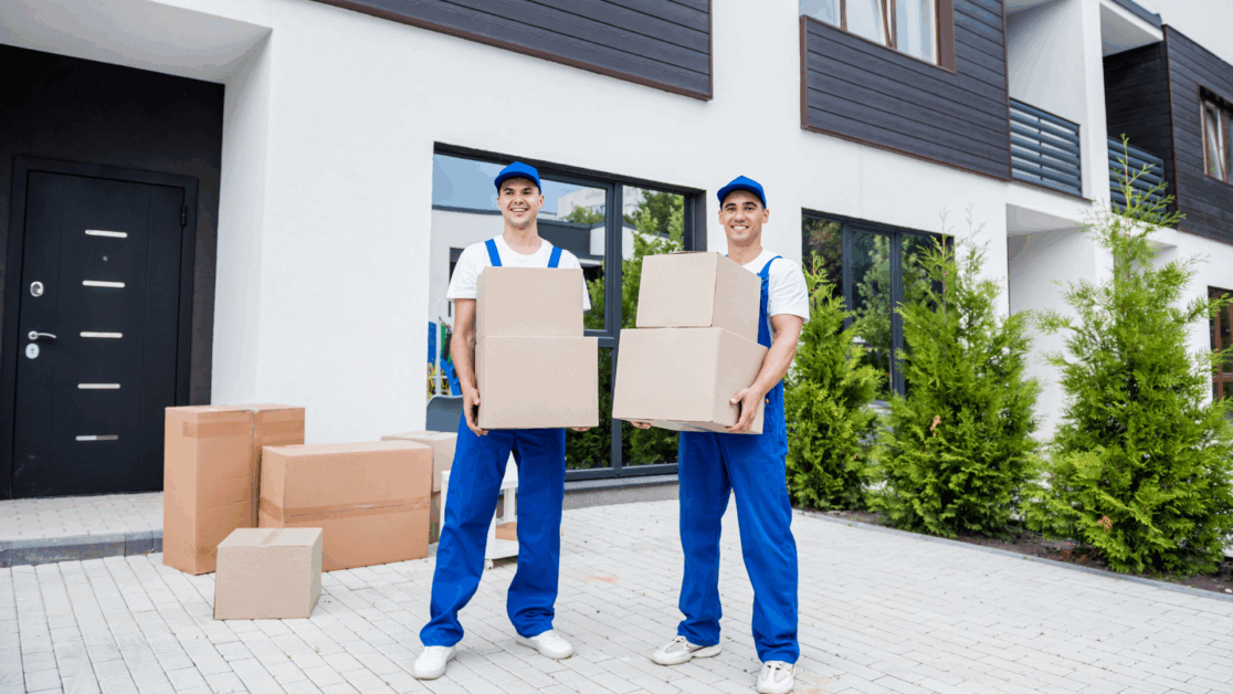 Two professional movers in Newark NJ holding cardboard boxes in front of a modern residential building, ready for a relocation task.